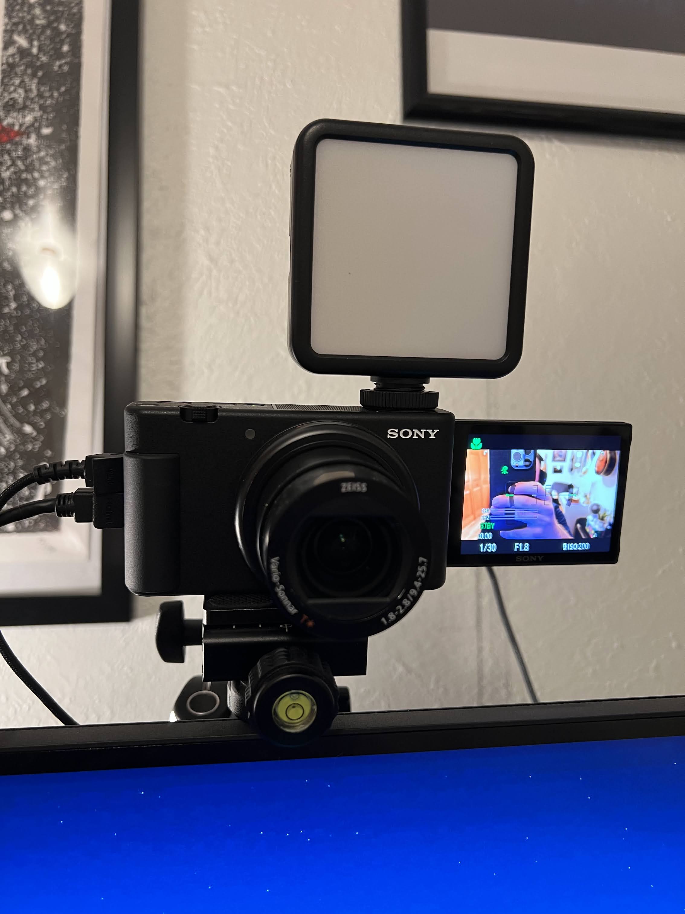 A picture of a webcam on a mount above a computer monitor.