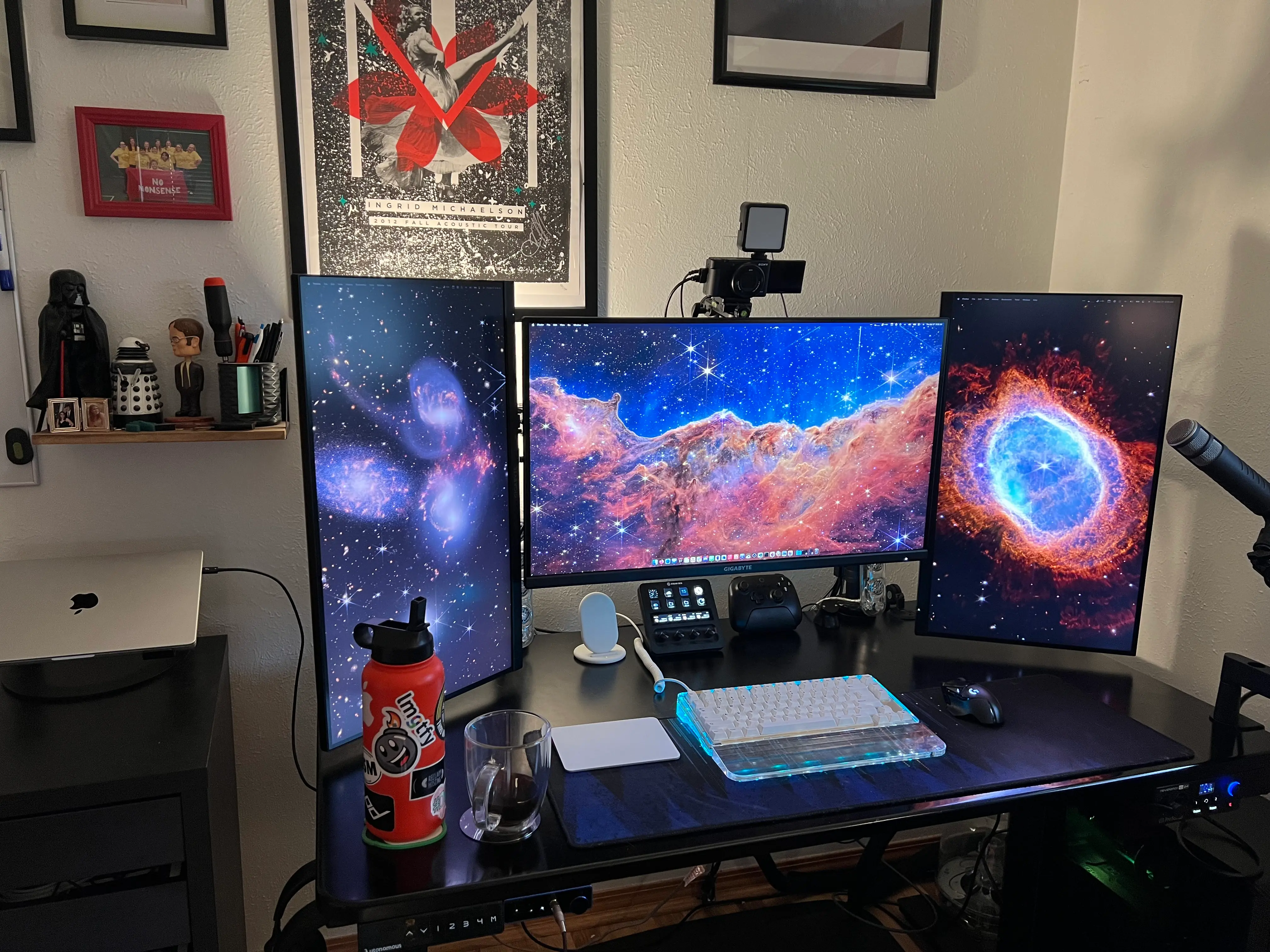 A picture of a desk with a keyboard, mouse trackpad and three monitors. One large center monitor, and two portrait monitors on either side of it.